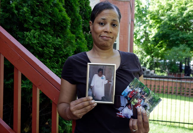 In this May 31, 2013 photo, breast cancer survivor Alicia Cook holds photos of family members who have also been afflicted by breast cancer, outside her home in Chicago. (AP Photo/M. Spencer Green)