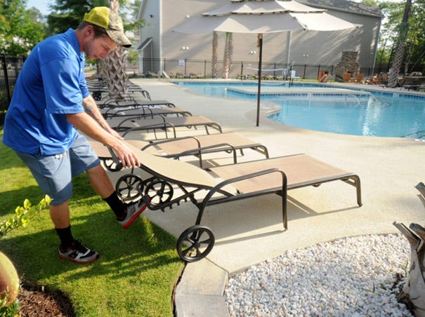 Camden Forest Apartments employee Kody Metcalf cleans up the pool area in the Camden Forest Apartments complex in Wilmington on July 24.