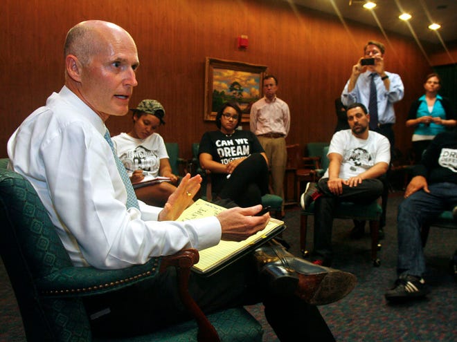 At left, Florida Gov. Rick Scott speaks to protesters Thursday July 18, 2013 in the Capitol in Tallahassee, Fla. Scott met with protesters who are participating in a sit-in at his office, organized by Dream Defenders in response to the not guilty verdict in the trial of George Zimmerman, the Florida neighborhood watch volunteer who fatally shot Trayvon Martin. Scott told protesters that he will not ask lawmakers to revamp the state's self-defense laws.