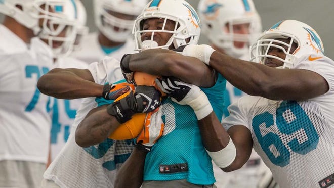 Miami Dolphins running back Lamar Miller (26) holds on tight during a drill at Dolphins training camp day 4. (Allen Eyestone/The Palm Beach Post)