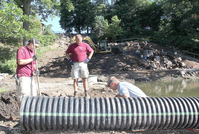 Ryan Brown (left) and Mike Schmid of Brickscape Creations & Landscaping work to level an area for a drainage tube at the Slayton Arboretum on the campus of Hillsdale College, while Larry Sinkovitz, company owner watches Thursday morning. The crew is renovating the waterfall at the arboretum.