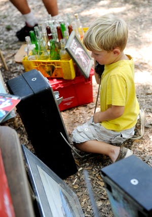 Samson Mallett, 4, of Leesburg, plays with a pay phone while his father shops around on Tabor Road during last year's sale.