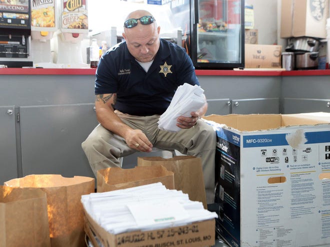 Detective Jody Foret sorts evidence at the Exxon on the corner of North Hollywood Road and West Park Avenue during a synthetic marijuana drug bust Jun. 26 in Houma.