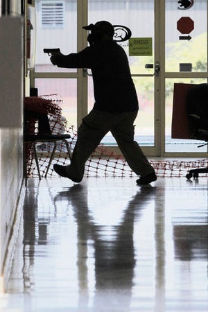 In this photo taken July 11, 2013, a Clarksville public schools faculty member, wearing a protective mask, participates in active-shooter training at the city's high school in Clarksville, Ark.