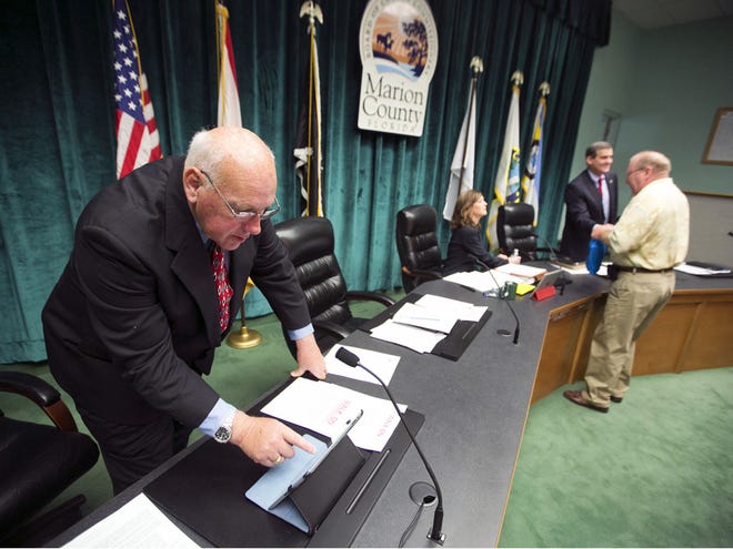 In this Nov. 20, 2012 file photo, Marion County Commission Earl Arnett works with an iPad shortly before he is sworn in at the County Commission meeting room in Ocala. Commissioners Kathy Bryant and Stan McClain also can be seen behind the desk. The commission is looking for ways to cut spending to avoid property tax increases.