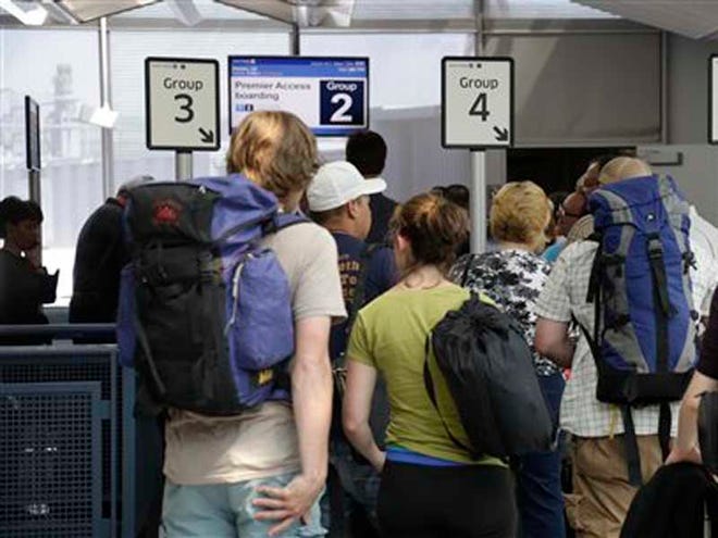 In this photo taken May 8, 2013, groups of passengers wait at a United Airlines gate to board a flight in separate numbered lanes at O'Hare International Airport in Chicago. For airlines, every minute that a plane sits at the gate makes it more likely that the flight will be late, hurting the carrier’s on-time rating and causing passengers to miss connecting flights. But the perfect boarding process remains elusive. Even an astrophysicist couldn’t figure it out. (AP Photo/M. Spencer Green)