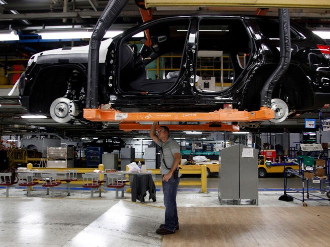 In this Wednesday, May 8, 2013 file photo, Jeff Caldwell, 29, right, a chassis assembly line supervisor, checks a vehicle on the assembly line at the Chrysler Jefferson North Assembly plant in Detroit.