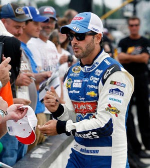 Jimmie Johnson signs autographs along the pits Friday as he waits to qualify for Sunday's Sprint Cup Series race at Pocono Raceway in Long Pond, Pa. Johnson won the pole with a speed of 180.654 mph.