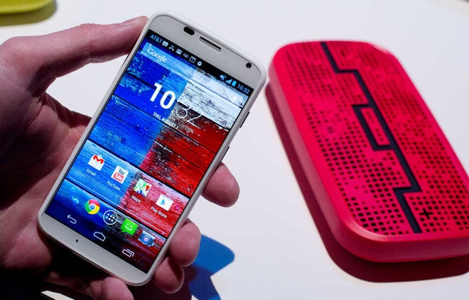 The Motorola Moto X smartphone, using Google's Android software, is displayed, Thursday, Aug. 1, 2013 at a press preview in New York. In the background is a Deck, from Sol Republic, which is a wireless speaker that operates up to 300 feet from the phone using Bluetooth technology. (AP Photo/Mark Lennihan)