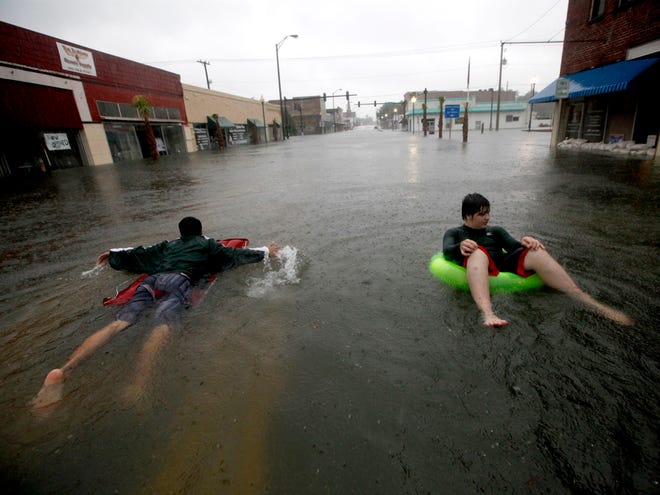 In this June 26, 2012 file photo, Austin Tinker, right, floats through floodwaters from Tropical Storm Debby in downtown Live Oak.