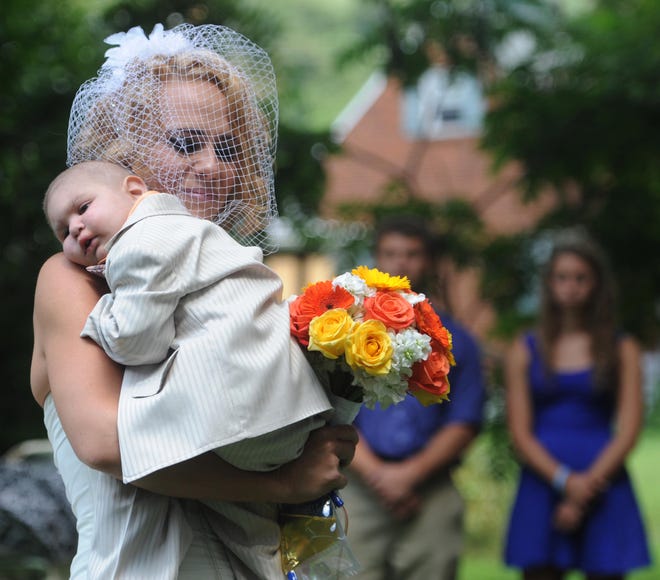 Christine Swidorsky carries her son and the couple's best man, Logan Stevenson, 2, down the aisle to her husband-to-be Sean Stevenson during the wedding ceremony on Saturday, Aug. 3, 2013 in Jeannette, Pa. Logan stood with his grandmother, Debbie Stevenson, during a 12-minute ceremony uniting Logan's mother and his father. The boy has leukemia and other complications. The Stevensons abandoned an original wedding date of July 2014 after learning from doctors late last month that their son had two to three weeks to live. The couple wanted Logan to see them marry and to be part of family photos. Logan, who was born Oct. 22, 2010, was diagnosed shortly after his first birthday with acute myeloid leukemia. He has Fanconi anemia, a rare disease that often leads to cancer.
