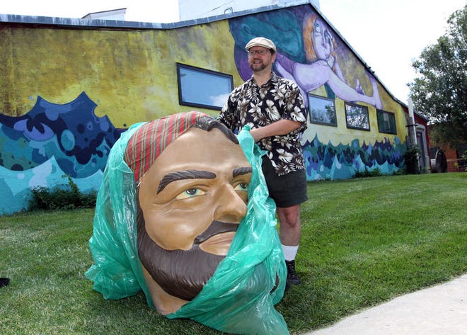 Greg Holmes unveils his fiberglass "Muffler Man" head in Hutchinson that he purchased from Greeley, Colo. A love for roadside attractions helped Holmes get a big head - and he is proud of it.