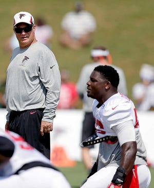 Atlanta Falcons head coach Mike Smith, left, looks on as linebacker Sean Weatherspoon, right, stretches during training camp at the NFL football team's practice facility on Thursday, Aug. 1, 2013, in Flowery Branch, Ga. (AP Photo/David Goldman)