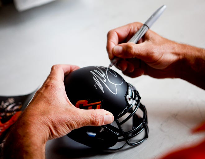 Oklahoma State head coach Mike Gundy signs a miniature helmet at fan appreciation day at Gallagher-Iba Arena in Stillwater on August 3, 2013. KT King, For The Oklahoman