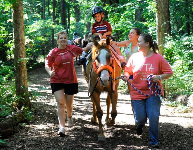 Brady Graft, 5, of Marshall trots on BJ the horse during a trail ride with Moberly Area Community College occupational therapy students, from left, Betsy White, Kayla Helton and Annie Cruse as they finish their final volunteer session Thursday at Cedar Creek Therapeutic Riding Center.