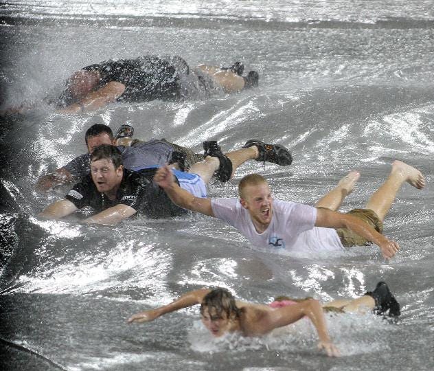 A group of people slide on the tarp covering the field during a rain delay in game 7 of the 2012 American Legion World Series. (Star file photo by Ben Earp)