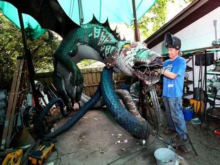 Artist John Andrews, who is a welder by trade, works to weld the final scales on the face of his dragon sculpture, which is mostly made of metal from shipping containers, at his home in Gainesville on Saturday. Andrews has built the more than 6,000 pound sculpture to enter in a art contest called Art Prize, which has a top prize of $200,000. Last year Andrews entered a smaller sitting dragon and placed in the top 25. Art Prize is a contest where the winner is voted on by fans over the internet.