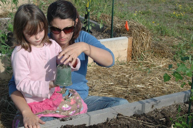 Scarlett Uhrig, age seven, with her mom, Lindsay Uhrig, plant vegetables at the Peck Community Gardens in Sault Ste. Marie on Monday.