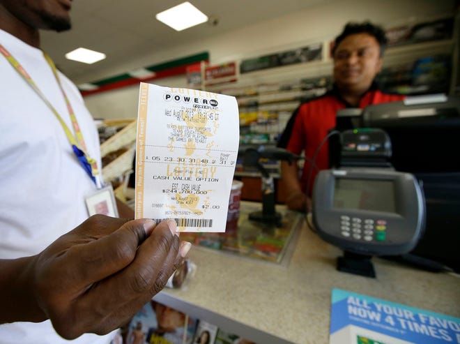 Raj Prasai, right, watches after making a sale to Eric, left, who did not want to give his last name in case he won the Powerball Jackpot, holds what he said would be the winning numbers after making the purchase, Wednesday, Aug. 7, 2013, in Dallas. The Powerball jackpot is expected to be about $425 million by Wednesday's drawing, making it the game's third largest ever.