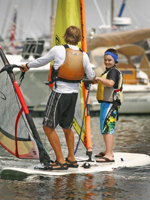 Gavin Chaisson, 10, gets lessons on a tandem windsurfer with Ross Lilley as part of the CORSE program at the Scituate Maritime Center on Monday, July 22, 2013.