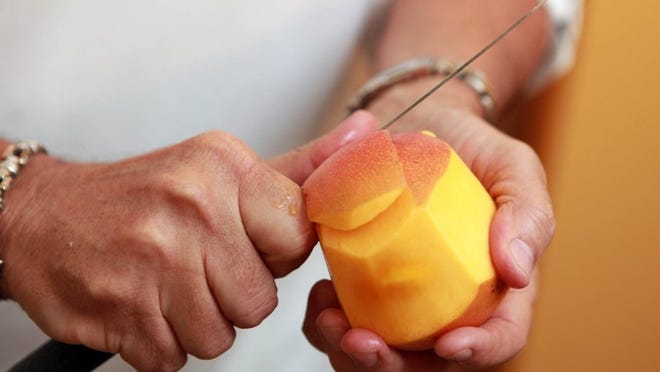 Owner Gustavo Garcia cuts a mango while preparing a milkshake at Copacabana restaurant in Jupiter. (Richard Graulich/The Palm Beach Post)
