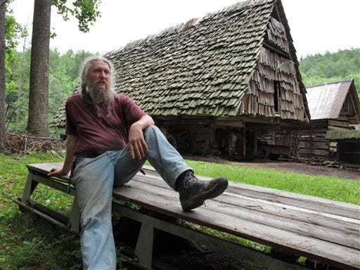 Eustace Conway rests on a wooden sledge in front of the horse barn at his Turtle Island Preserve in Triplett, N.C., on Thursday, June 27, 2013. People come from all over the world to learn natural living and how to go off-grid, but local officials ordered the place closed over health and safety concerns. (AP Photo/Allen Breed)