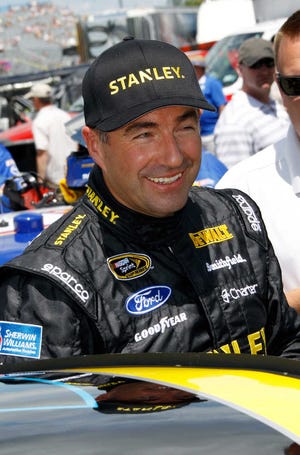 Marcos Ambrose smiles as he gets out of his race car, after qualifying on the pole for Sunday's NASCAR Sprint Cup Series auto race, Saturday Aug. 10, 2013, in Watkins Glen, N.Y. Ambrose took the pole with 128.241 miles per hour. (AP Photo/Russ Hamilton Sr.)