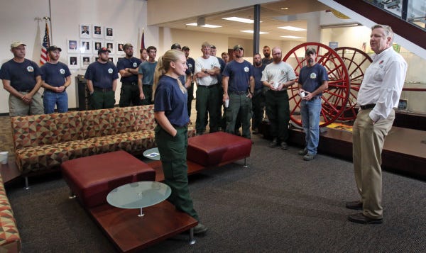 Firefighter Casey Burdick, center, was the only woman on a team of 20 firefighters that just returned from battling Western wildfires. Yesterday at the Ohio Fire Academy, Burdick and the others were welcomed home by Jim Zehringer, right, the director of the Ohio Department of Natural Resources.