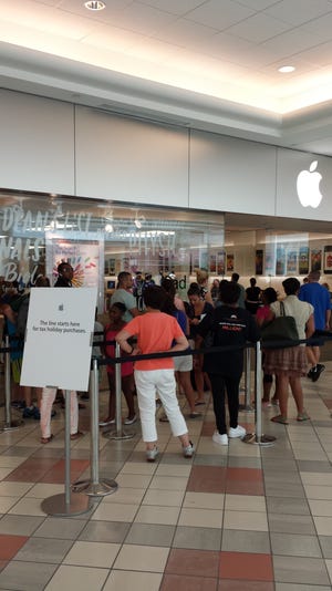 Customers wait in line to make purchases at the Apple store at South Shore Plaza.