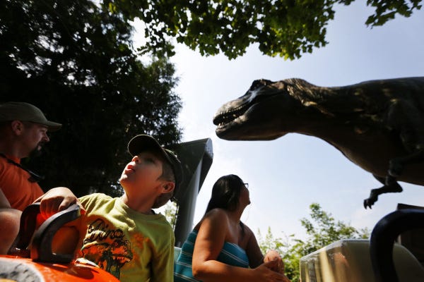 Joseph Foraker, 4, spots another dinosaur as father Joe and mother Sarah eye the          T. rex at the Columbus Zoo and Aquarium.