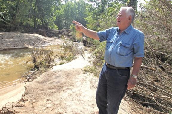 Jack Spangler shows damage caused when recent flooding in the Belwood area destroyed the old Rockdale Mill area dam.