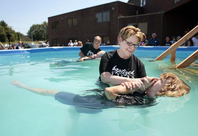 Pastor Dawn Stuemke baptizes Delaine Sparks as Pastor Paul Rose baptizes Sparks’ husband, Bruce, on Sunday at Calvary Temple Christian Center. More than 100 people were baptized during the outdoor ceremony.
