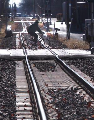 Looking due south in downtown Springfield, a bicyclist crosses the Third St. railroad tracks on Friday, Nov. 23, 2012. Even though realignment of rail traffic will be on 10th Street, many upgrades will be needed along the Third St. rail corridor.