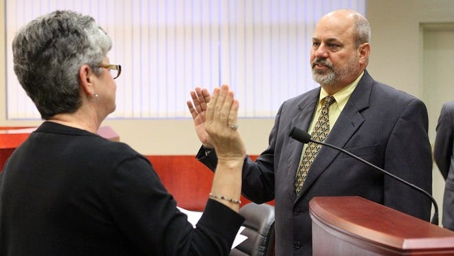 Greenacres City Clerk Denise McGrew administers the oath of office to longtime Mayor Sam Ferreri during a city council meeting on Monday. City council members John Tharp and Paula Bousquet were also sworn in for second terms. All three were automatically reelected because nobody filed qualifying papers to run against them.