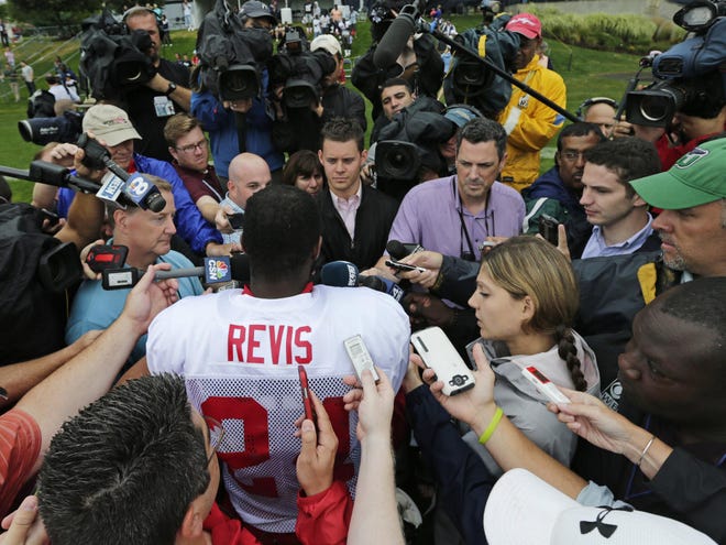 Tampa Bay Buccaneers cornerback Darrelle Revis is surrounded by reporters Tuesday after a joint workout with the New England Patriots at NFL football training camp, in Foxborough, Mass.