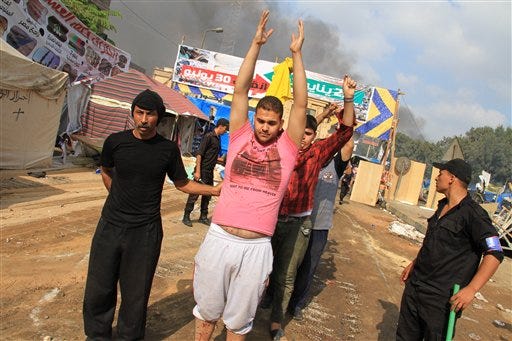 Egyptian security forces detain protesters as they clear a sit-in by supporters ousted Islamist President Mohammed Morsi in the eastern Nasr City district of Cairo, Egypt, Wednesday, Aug. 14, 2013. Egyptian security forces, backed by armored cars and bulldozers, moved on Wednesday to clear two sit-in camps by supporters of the country's ousted President Mohammed Morsi, showering protesters with tear gas as the sound of gunfire rang out at both sites. (AP Photo/Ahmed Gomaa)