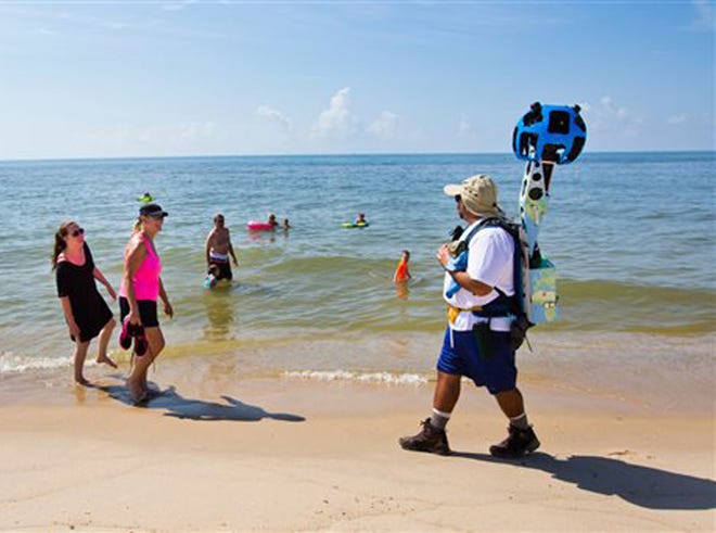 In this photo taken July 30, 2013, and made available by Visit Florida, Gregg Matthews carries a Google street view camera as he walks recording St. George Island beach in the Florida Panhandle. Visit Florida, the state's tourism agency, partnered with Google in the effort to map all 825 miles of Florida’s beaches. The Florida project is the first large-scale beach mapping project.