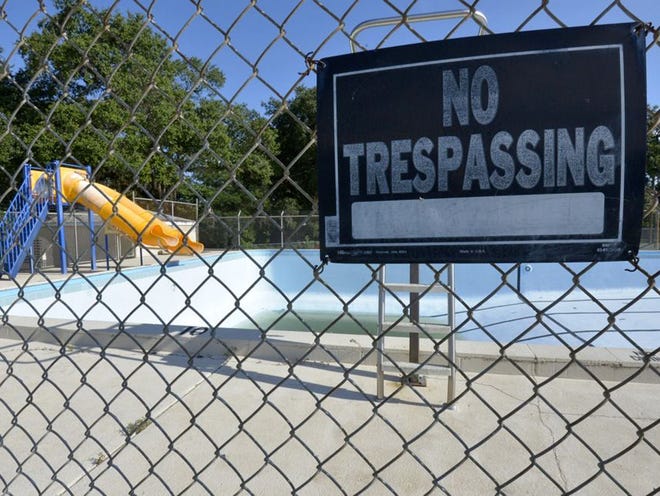 A "NO TRESPASSING" sign  hangs on the fenced-in Dolphus Howard pool on Thursday at the Citrus Center Boys and Girls Club in Haines City. The pool is empty except for accumulated rainwater.