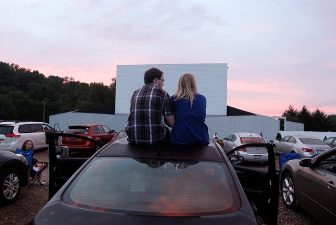 In this July 20, 2013 photo, Alex Lockhart, left, and Mikayla Green, both of Newark, watch the sunset while waiting for the movie to start at the Skyview drive-in theater in Lancaster, Ohio. The Skyview was the first drive-in theater in Ohio to convert to a digital projector. The latest threat to the existence of drive-in theaters is the conversion from 35mm film to digital prints and the expense involved in converting projectors to the new format. (AP Photo/Jay LaPrete)