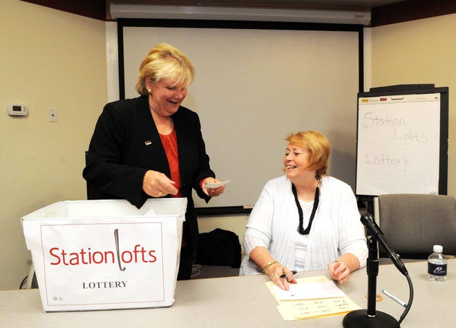 Brockton Mayor Linda Balzotti, left, draws numbers and hands them to Laurie McGuire at the Station Lofts housing lottery held at the Metro South Chamber of Commerce on Thursday, Aug. 15, 2013.