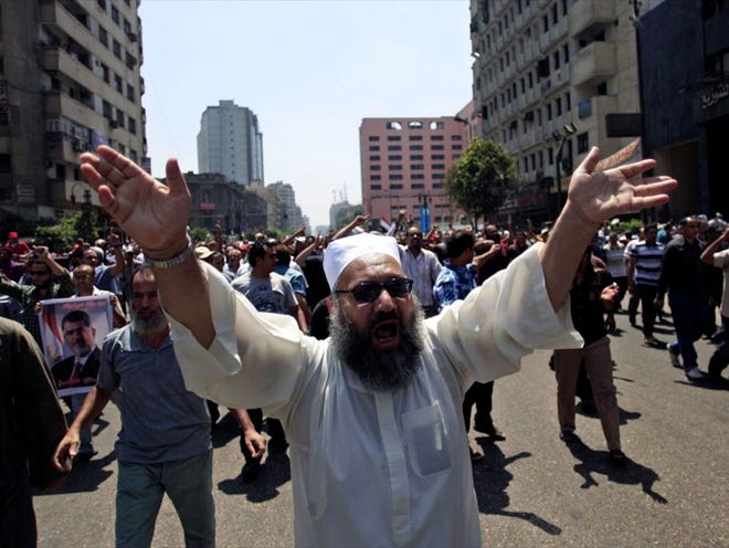 Supporters of Egypt's ousted President Mohammed Morsi chant slogans during a protest in Ramses Square in downtown Cairo, Egypt, Friday, Aug. 16, 2013. Heavy gunfire rang out Friday throughout Cairo as tens of thousands of Muslim Brotherhood supporters clashed with vigilante residents in the fiercest street battles to engulf the capital since the country's Arab Spring uprising. Tens of people were killed in the fighting nationwide, including police officers. (AP Photo/Khalil Hamra)