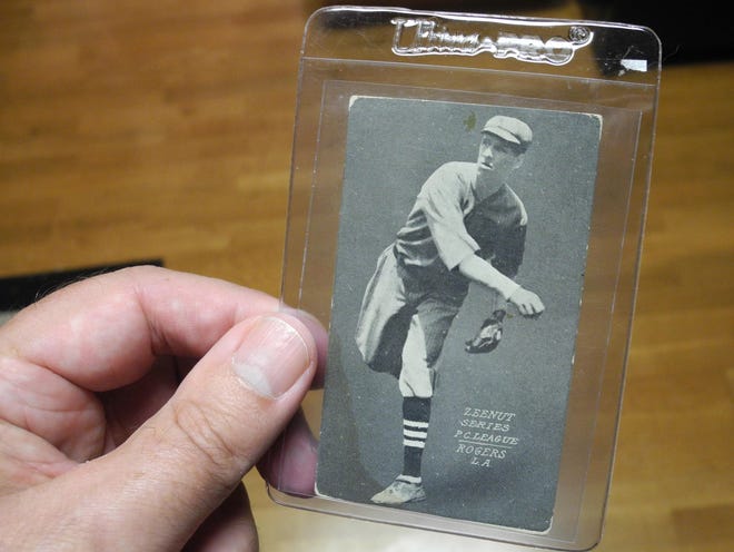 Tom Priddy holds a baseball card depicting his grandfather, Brown Rogers, who played minor league baseball for seven seasons a century ago. This card is from the 1914 Zeenut series, showing Rogers with the Los Angeles Angels of the Pacific Coast League.