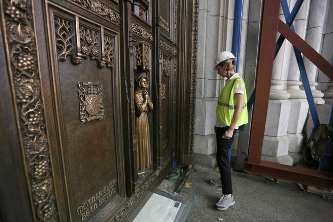 Lucia Popian inspects one of the bronze doors Tuesday after it was reinstalled at St. Patrick's Cathedral in New York. The $550,000 conservation and restoration took three months.