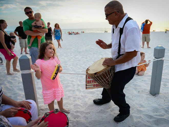 Trinity Gonzalez, 6, plays the tambourine while Edsel Van De Wall Arnemann plays his djembe Friday, August 16 at the drum circle on Holmes Beach.