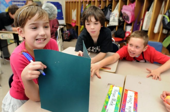 (FILE PHOTO) New Hope-Solebury Upper Elementary School fourth-graders Morgan Miele (left) hides her answers from her other classmates as Jake Schmukler (middle) and Jake Saxton (right) give their input during a T.AK.L.E session. New Hope-Solebury high school student volunteer?s work with elementary students as part of the T.A.K.L.E program, high school kids learn to mentor elementary age kids.