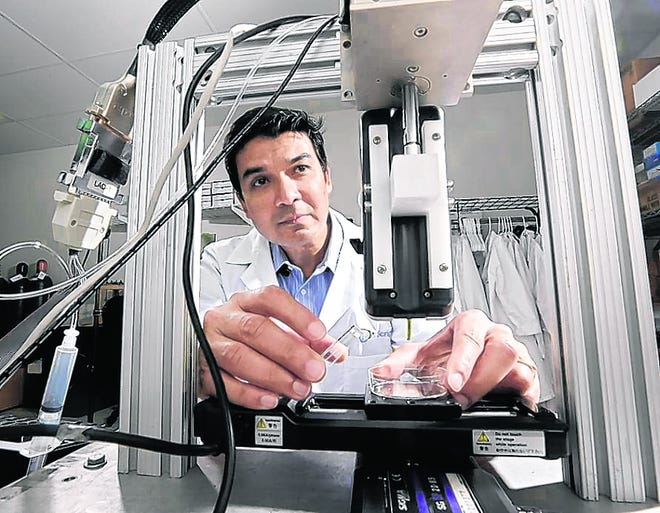 In laboratories around the world, researchers are experimenting with a 
high-tech way to create body tissue, but there are many obstacles in what is 
known as bioprinting. Above, Dr. Darryl D'Lima works last week with a 
bioprinter that he helped develop in a laboratory at the Scripps Clinic in 
San Diego.NYT PHOTO / SANDY HUFFAKER