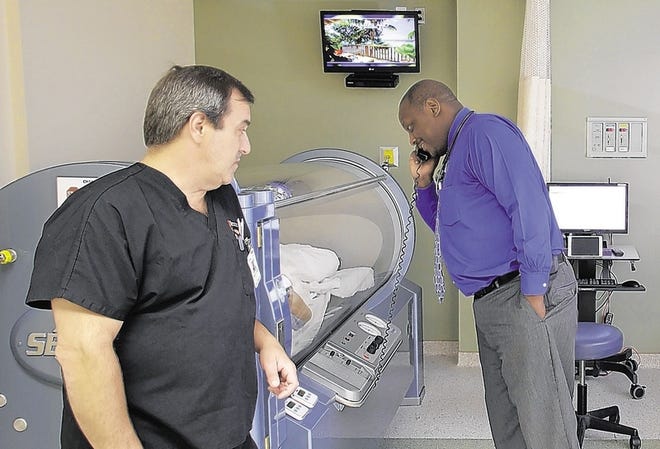 Cobey Jones, program director of the Catskill Regional Wound Healing Center in Harris, talks to a patient undergoing hyperbaric oxygen therapy. Christopher Hartman, clinical manager of the Wound Care Department, is at left.