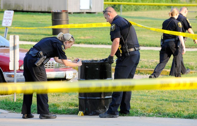 Columbia police officers photograph a bullet hole in a trash can Wednesday after responding to shots fired at Douglass Park. No injuries were reported.