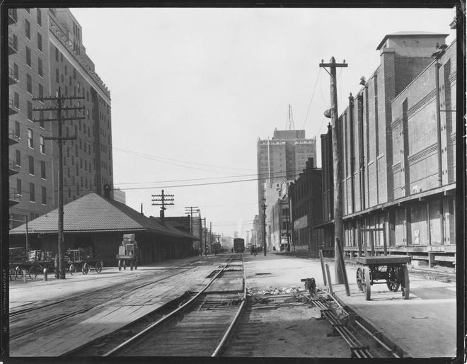 TRAIN / RAILROAD / TRAIN STATION: Caption reads, "The large building at left is the Skirvin Plaza. The small building beside it was the Rock Island station. The view is westward from the site of Santa Fe Plaza toward what is now Couch Drive." Undated original (before 1930). Photographer unknown. Published on 11/14/1982 in The Daily Oklahoman.