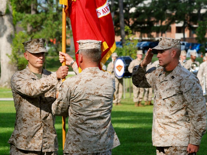 Col. Chris Pappas III, left, receives the MCAS Cherry Point colors from Col. Philip J. Zimmerman as air station Sgt. Maj. Benjamin Pangborn salutes at right during a change of command ceremony Thursday.